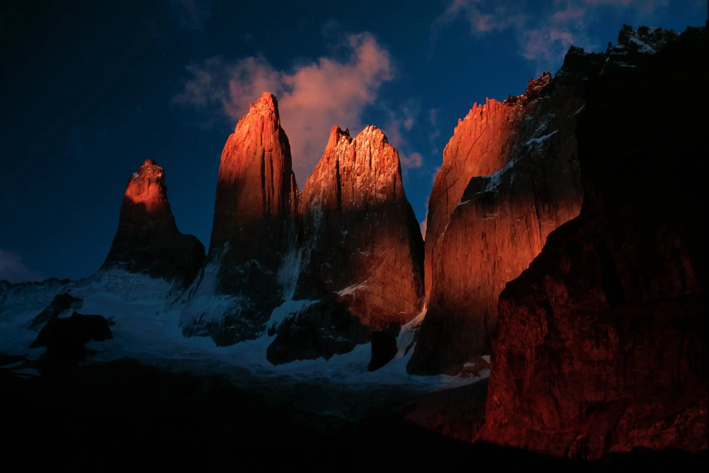 As Torres del Paine acesas pelo sol nascente, sobre o vale ainda escuro